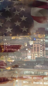 Vertical video: US flag rippling over night city, wind causing glass overlay shifting with haze