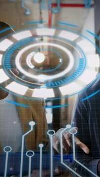 Vertical video: Team at glass display for tech demo, HUD pulsing, hands tapping holographic ring