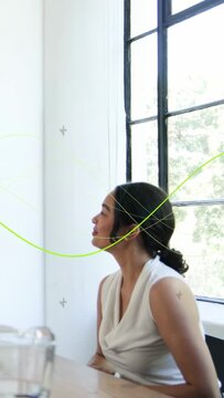 Vertical video: Woman seated by window reacting to lime line sweeping across pad for design review