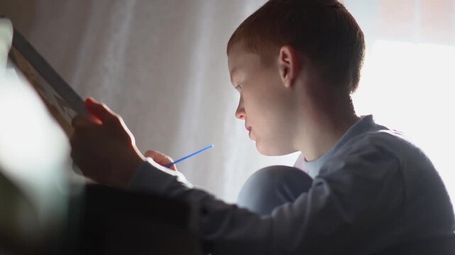 A teenager paints a paint-by-numbers picture on canvas with a brush. A boy dips a brush into paint and creates a creative drawing on a canvas. High quality FullHD footage
