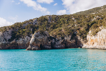 Obraz premium Cala Luna beach with turquoise water and dramatic cliffs in the Gulf of Orosei, Sardinia, Italy, during summer