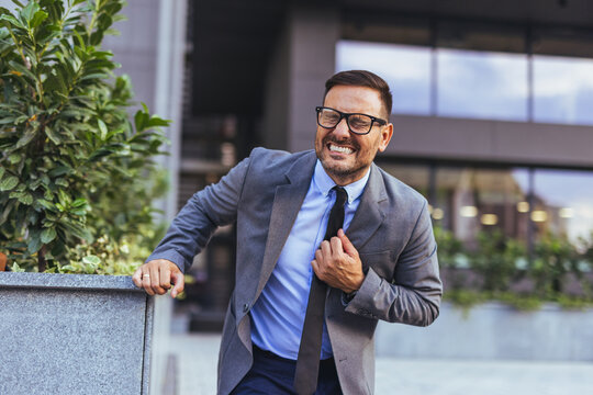 Businessman Clutching Chest in Pain Outside Office Building Showing Stress and Possible Heart Attack