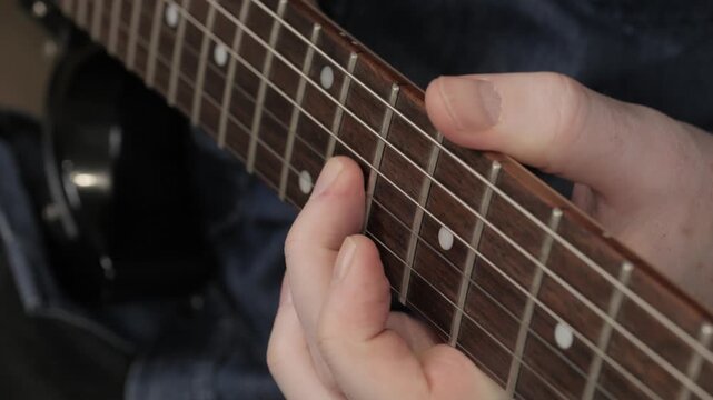 play electric guitar close up fingers slide over strings of electric guitar
