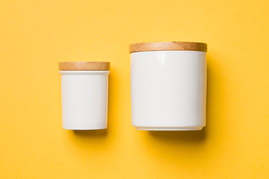 White ceramic kitchen canisters with wooden lids on a yellow background