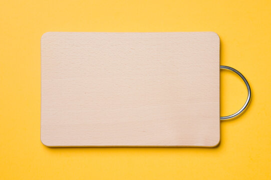 Wooden cutting board for bread on a yellow background