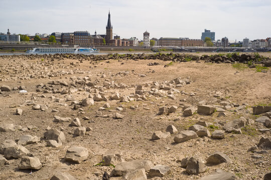 Low stream gauge of rhine river.Water shortage, drought, climate change,global warming concept, dry river bed with skyline of the town of d&uuml;sseldorf, germany in the background