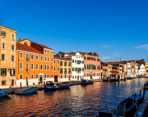 Fototapeta premium city of Venice with beautiful old buildings near embarkment of a canal wirh boats and water and beautiful cloudy sky on background