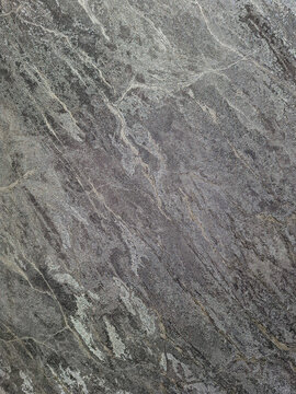 Dark grey stone surface with natural mineral veins and textured finish captured from a high angle close up