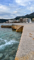 Fototapeta premium Dobra Voda waterfront along Adriatic Sea with concrete pier and coastal buildings