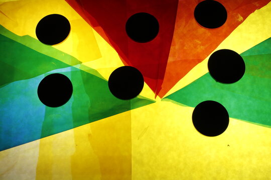 Composici&oacute;n abstracta formada por papeles de seda transl&uacute;cidos superpuestos en formas triangulares que convergen hacia un punto central, creando un efecto radial din&aacute;mico en la paleta de colores.     