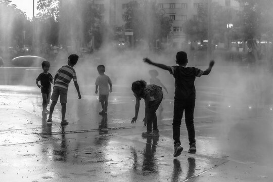 Vienne (Autriche, Europe) - Vue monochrome de jeux d'eau d'un groupe d'enfants sur la place Praterstern &agrave; la tomb&eacute;e de la nuit en &eacute;t&eacute;