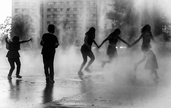 Vienne (Autriche, Europe) - Vue monochrome de jeux d'eau d'un groupe d'enfants sur la place Praterstern &agrave; la tomb&eacute;e de la nuit en &eacute;t&eacute;