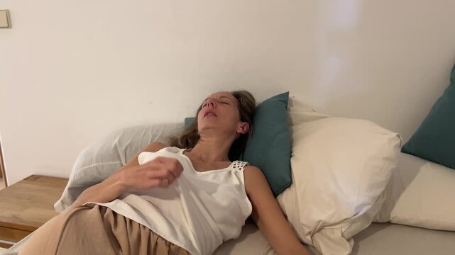 Mujer en la cama destap&aacute;ndose por sofocos de la menopausia