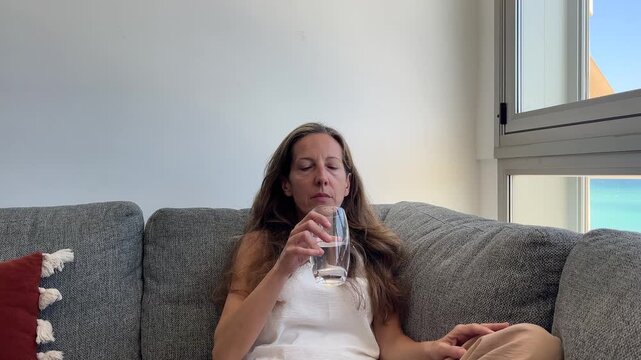 Mujer tomando pastillas para aliviar s&iacute;ntomas de la menopausia