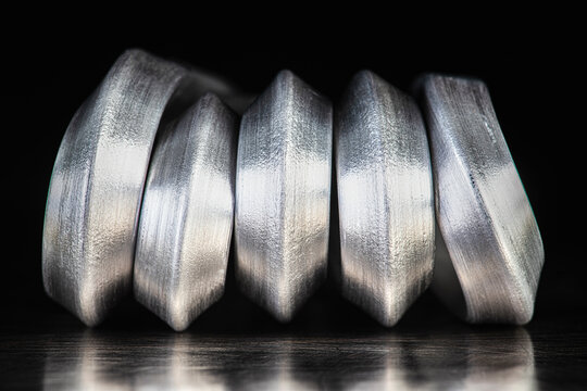Bent aluminum rods placed on a metal surface in an industrial setting. Malleability and lightness of nonferrous metals used as raw materials in the metallurgical and manufacturing industries
