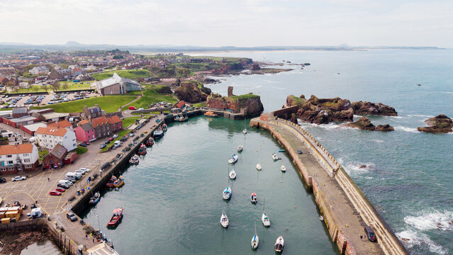 Historic Dunbar Harbour and medieval castle ruins on rugged cliffs overlooking the North Sea in East Lothian Scotland