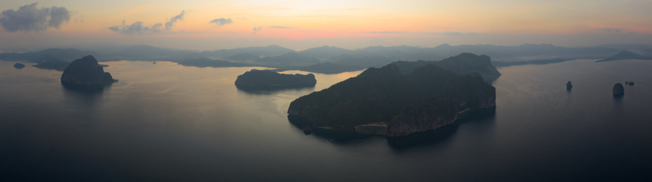 Sunrise silhouettes dramatic limestone islands in Bacuit Bay, El Nido, at sunset. This area in the Philippines is a popular vacation destination due to its coral reefs, beaches, and hidden lagoons.