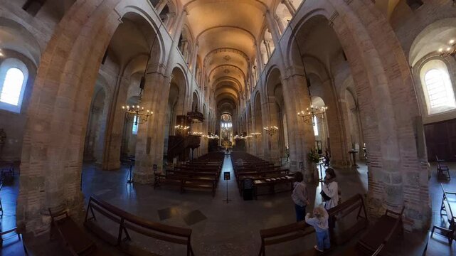 Interior of stone cathedral nave with vaulted ceiling and chandeliers