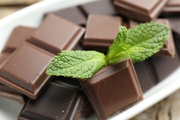 Pieces of yummy chocolate and mint leaves on table, closeup © New Africa