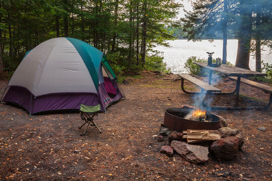 Campsite with tent fire picnic table and gear by a lake in a northern Minnesota state forest at dusk