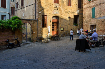 Obraz premium Medieval narrow street with tables of restaurant in Siena, Tuscany, Italy. Architecture and landmark of Siena. Cozy cityscape of Siena in Siena, Tuscany, Italy.