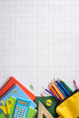 Back to school vertical supplies layout with colored pencils, notebooks, calculator and ruler on graph paper © ActionGP