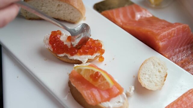 bread with butter and red caviar. red caviar being placed on buttered multigrain bread using a spoon. A can of salmon roe, butter, bread lie on wooden surface, creating a rustic and gourmet breakfast
