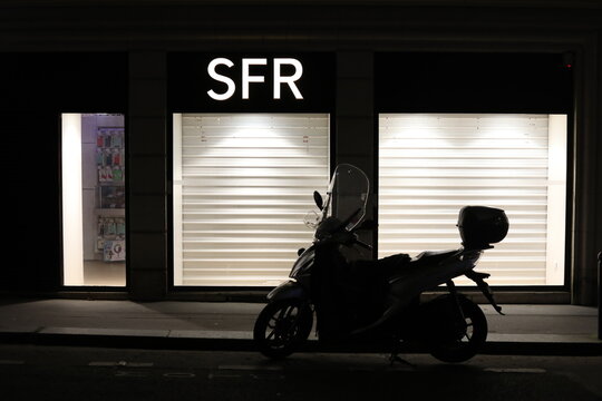 Paris, France - February 23, 2026. A closed and illuminated SFR store by night.