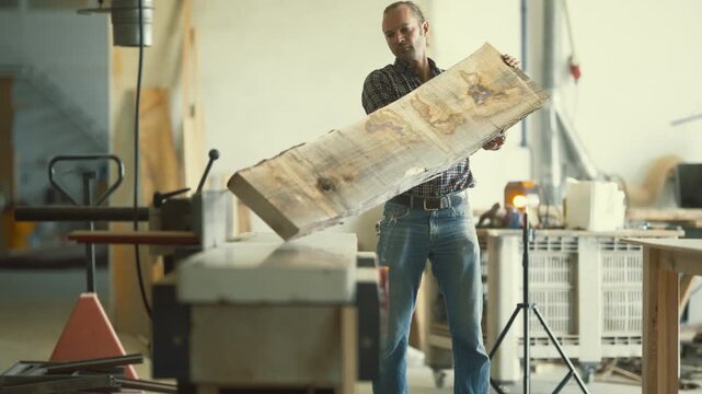 Carpenter processing a raw wooden plank on a jointer machine