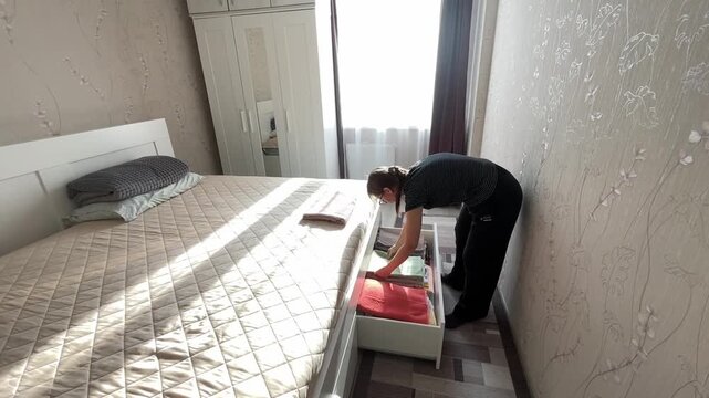 Woman carefully organizing bedroom furniture. Gentle woman arranges linens with calm precision. Woman meticulously arranges her bedroom essentials in calm and friendly morning routine