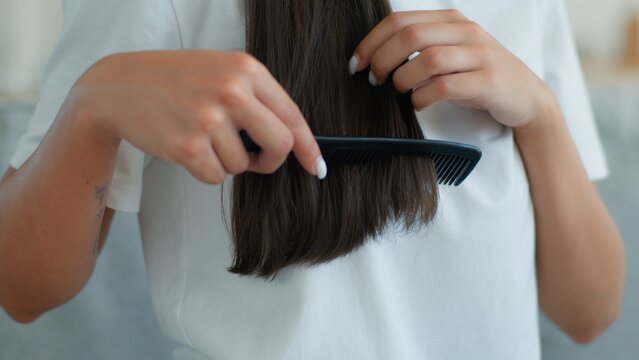 Cropped unrecognizable woman brushing dark hair combing at home indoor healthy female girl haircare routine using brush conditioner shampoo mask cosmetic smooth hairstyle hairstyling beauty treatment