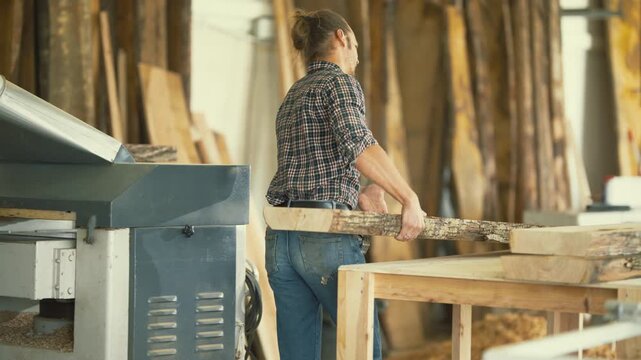 Carpenter processing raw timber on a planer machine