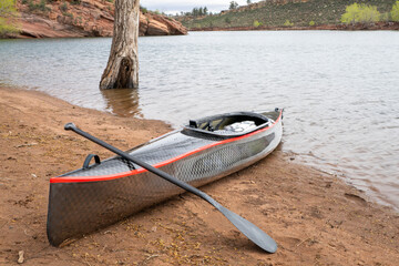decked touring canoe with carbon fiber hull and rudder at a shore of calm lake © MarekPhotoDesign.com