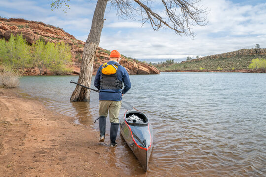 senior paddler and his decked touring canoe on shore of Horsetooth Reservoir - early spring scenery of Colorado foothills