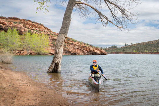 senior paddler is paddling a decked touring canoe on Horsetooth Reservoir - early spring scenery of Colorado foothills