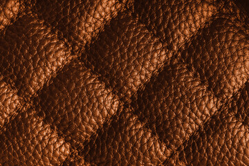 Fototapeta premium Close up, macro of orange quilted leather texture with stitched diamond pattern, luxury material surface shining metal effect for fashion, upholstery or design wallpaper, rough, relief background