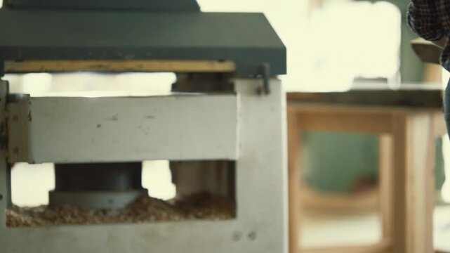Carpenter processing wood plank using thickness planer machine