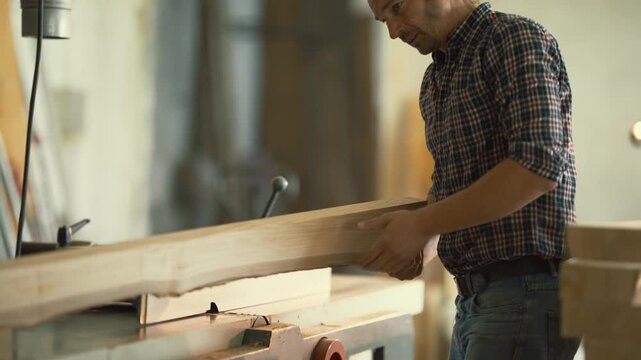 Carpenter using a jointer machine to plane wood plank in a workshop