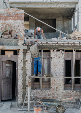 Cuba, Cienfuegos.  Two men work to restore old stone house.  