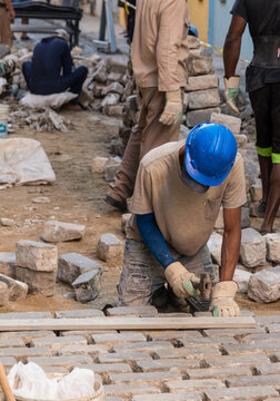 Cuba, Cienfuegos.  Workers laying stone blocks for cobbled street.