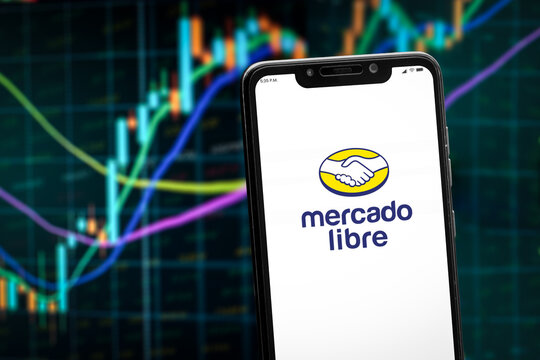 Cali, Colombia - January 12 2026: "Mercado libre" app logo on the smartphone screen and the bull chart of stock market at the blurred background.
