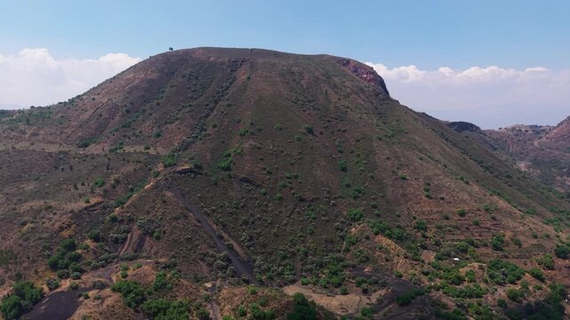 Cinematic drone ascend over a rugged volcanic mountain with a hiking trail, 4K D-Log