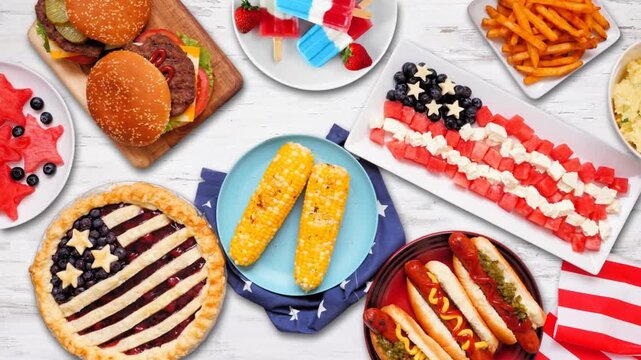 Fourth of July, patriotic, American themed food. Stop motion table placement loopable video. Above view on a white wood background.