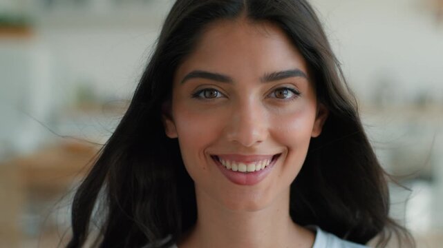 Smiling Indian Arabian woman looking at camera with healthy toothy smile home indoors female portrait young happy satisfied glad positive girl blowing flying hair air conditioner wind beauty dentistry