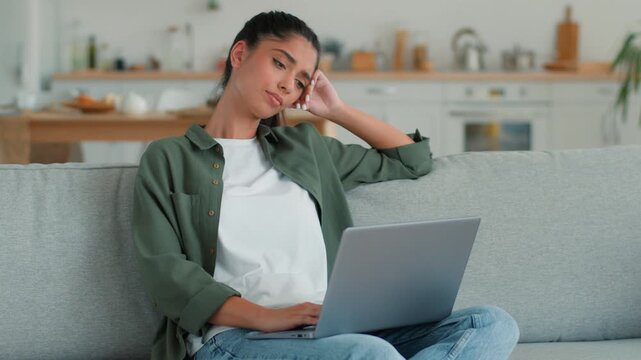 Sad frustrated Indian woman at home using laptop mobile phone upset online shopping problem tired stressed lost disappointed Arabian female girl customer buyer client chatting cellphone failure indoor