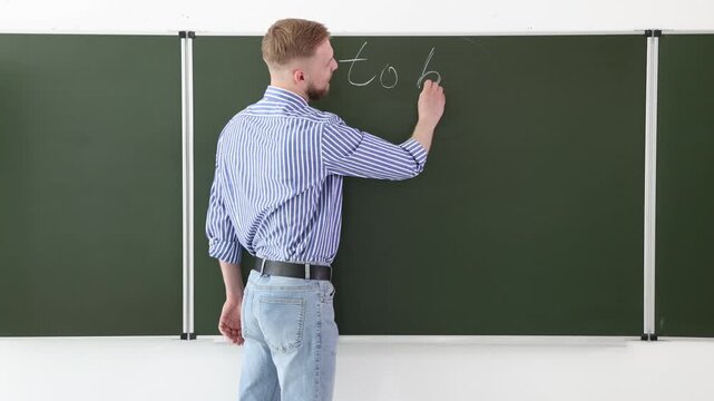 English teacher explaining verb to be at green chalkboard in classroom