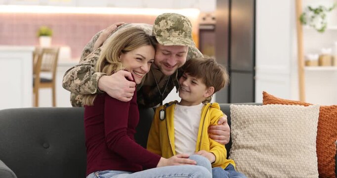 Man in military uniform hugging his family at home