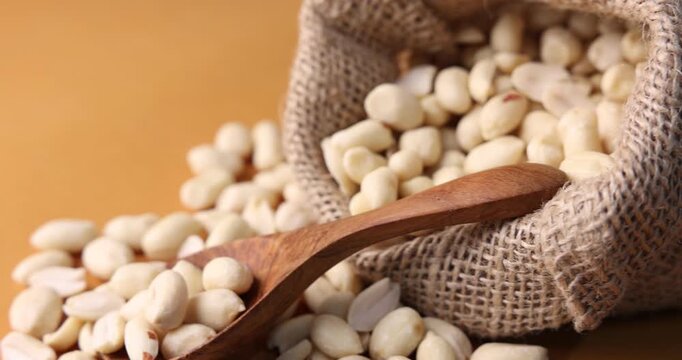 Peanuts in sack on brown background, spinning. Closeup view