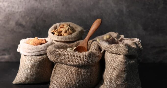 Different types of nuts in bags on black table. Casting light and shadow