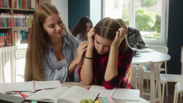 Crying Caucasian girl child sad after bullying friend comforting apologizing in classroom conflict resolution teen girls friendship support empathy education schoolgirls school students talking indoor